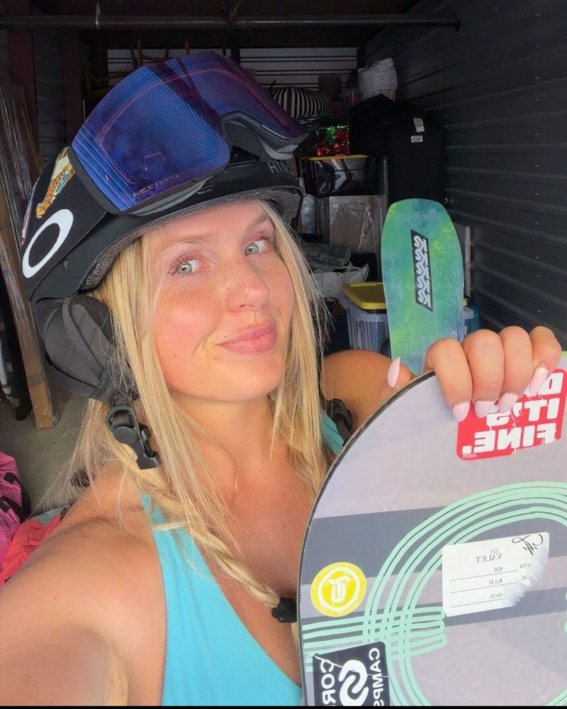 Ash in a snowboard helmet with goggles, holding up her snowboard